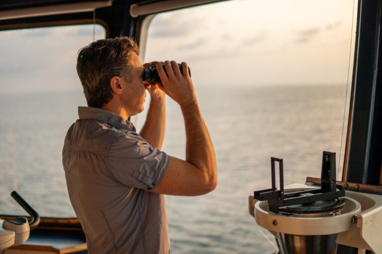Mariner keeping lookout with binoculars on a ship's bridge