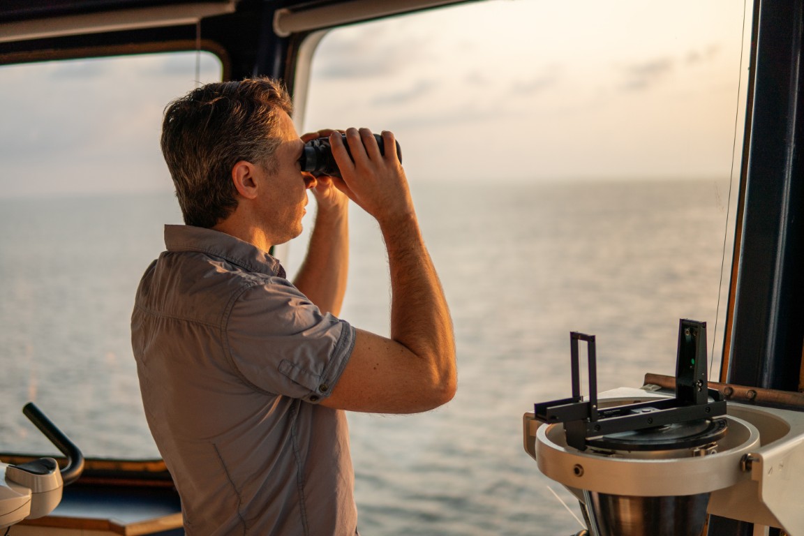 Mariner keeping lookout with binoculars on a ship's bridge