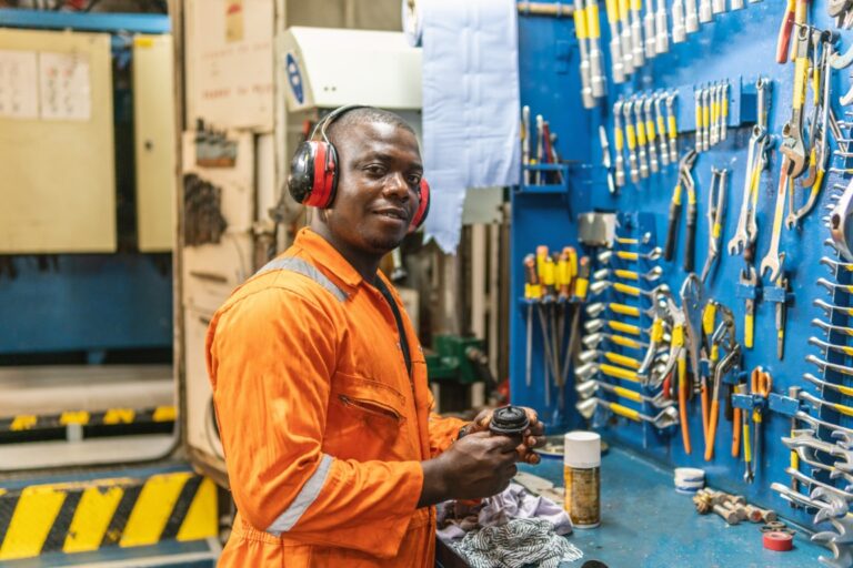 Marine engineer in coveralls at a ship's engine room workbench
