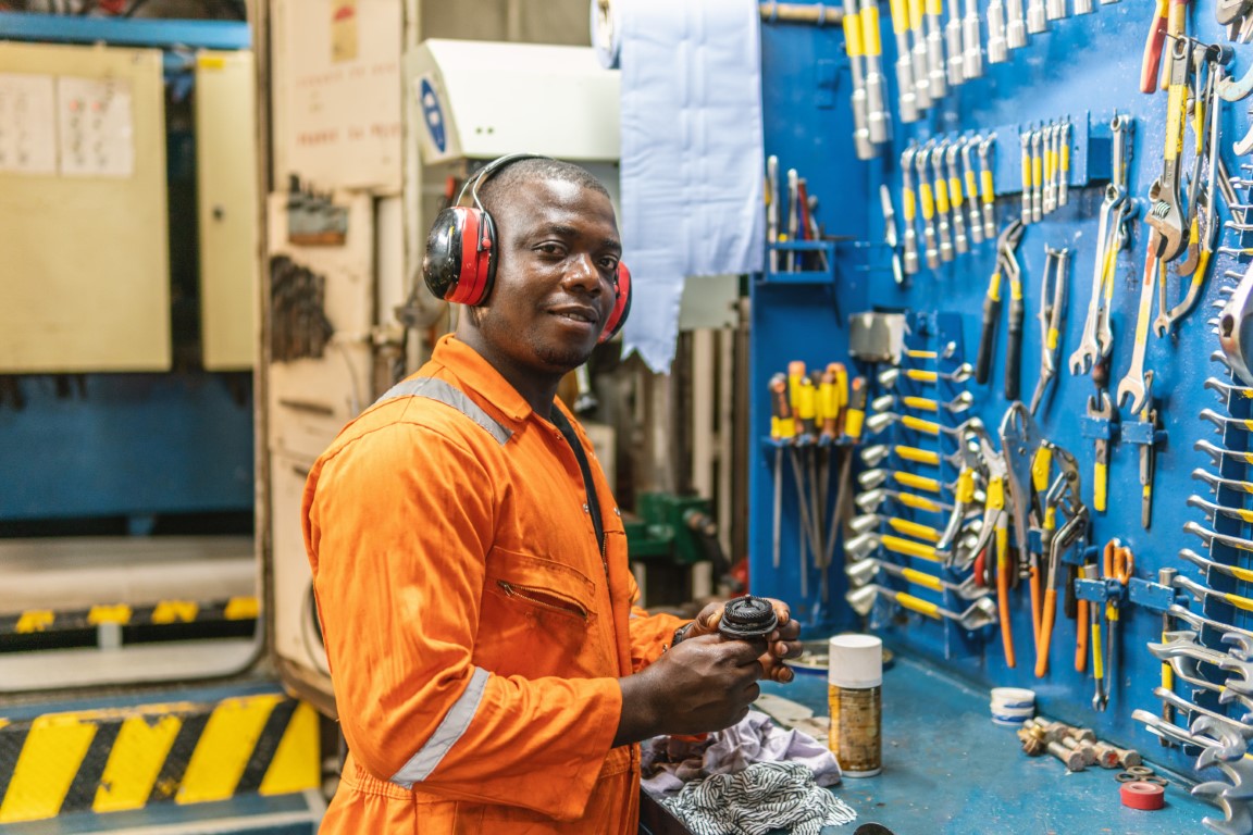 Marine engineer in coveralls at a ship's engine room workbench